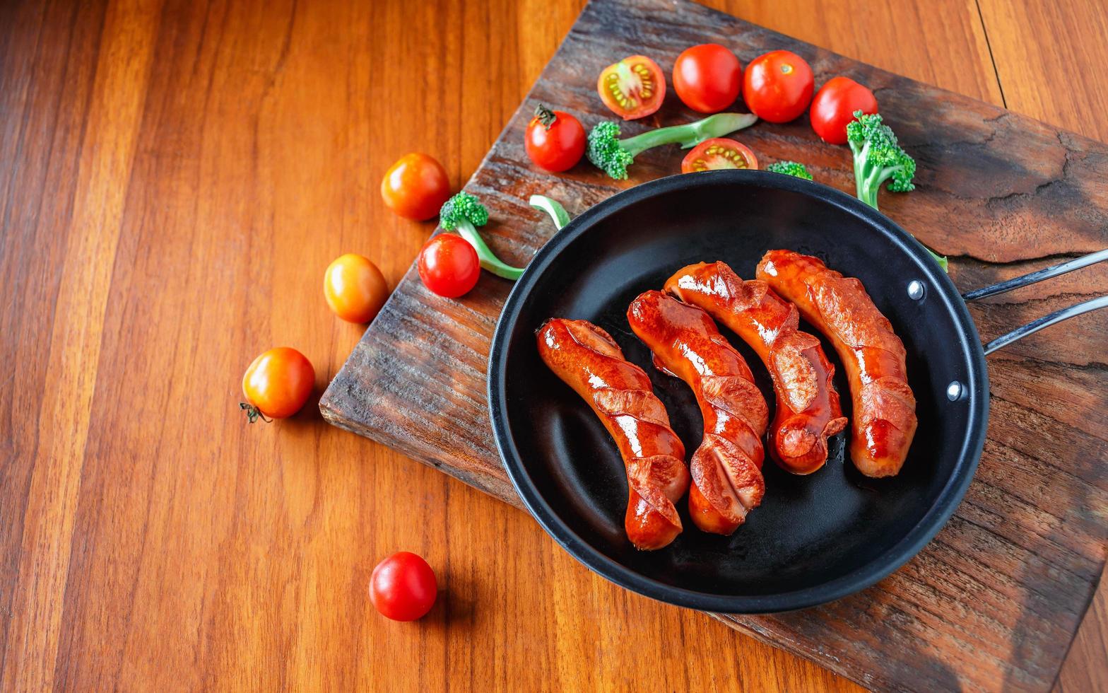 Fried sausages in a pan with tomatoes and broccoli photo