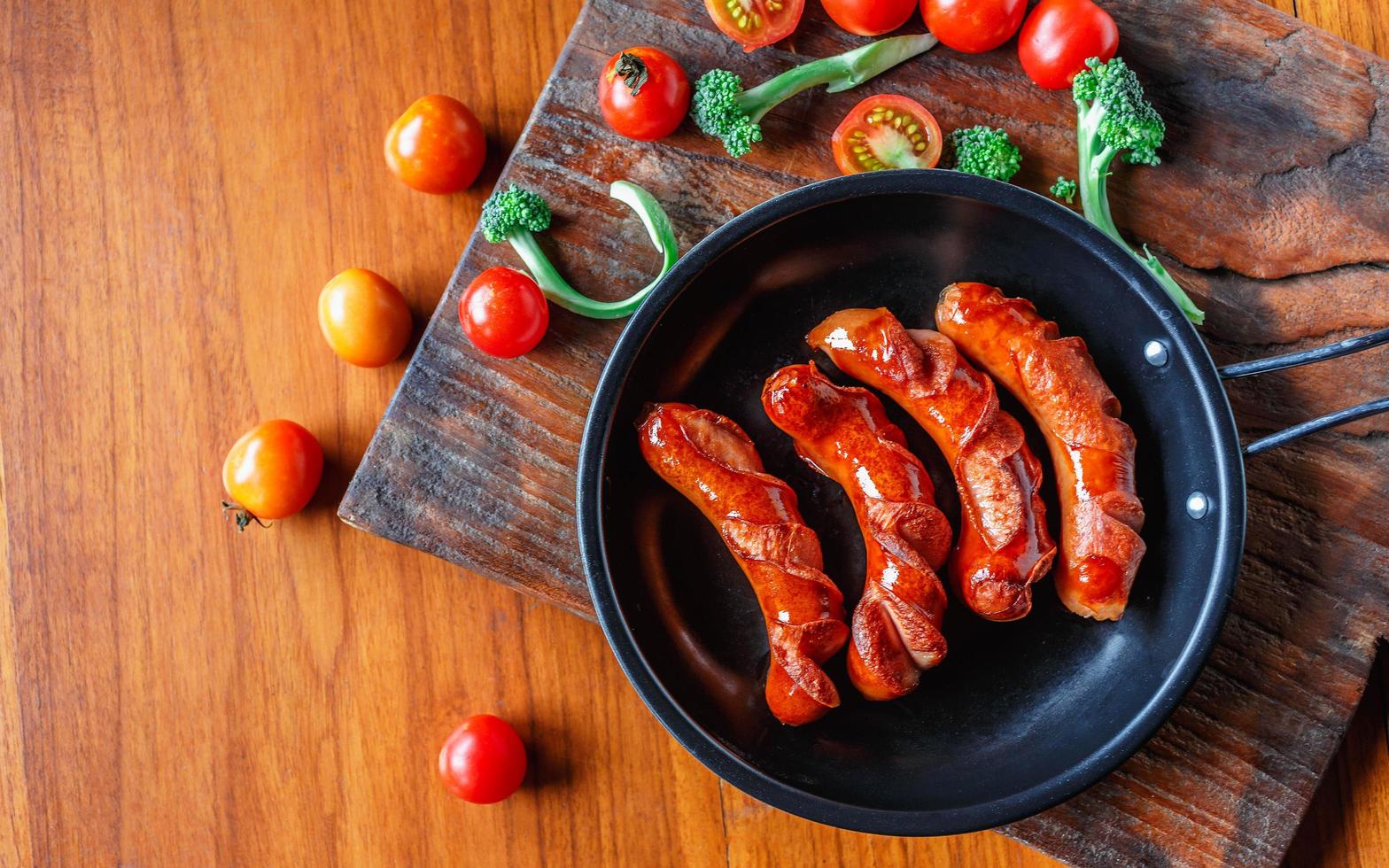 Fried sausages in a pan with tomatoes and broccoli photo