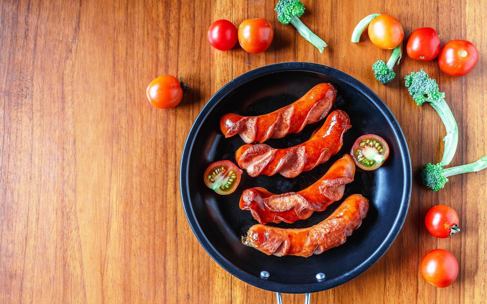 Fried sausages in a pan with tomatoes and broccoli photo