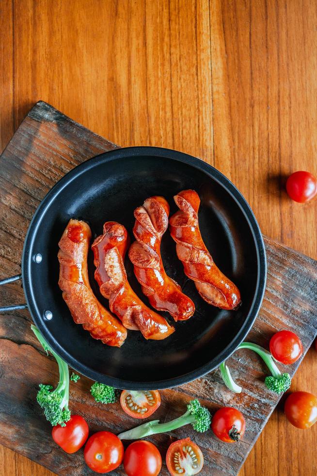 Fried sausages in a pan with tomatoes and broccoli photo