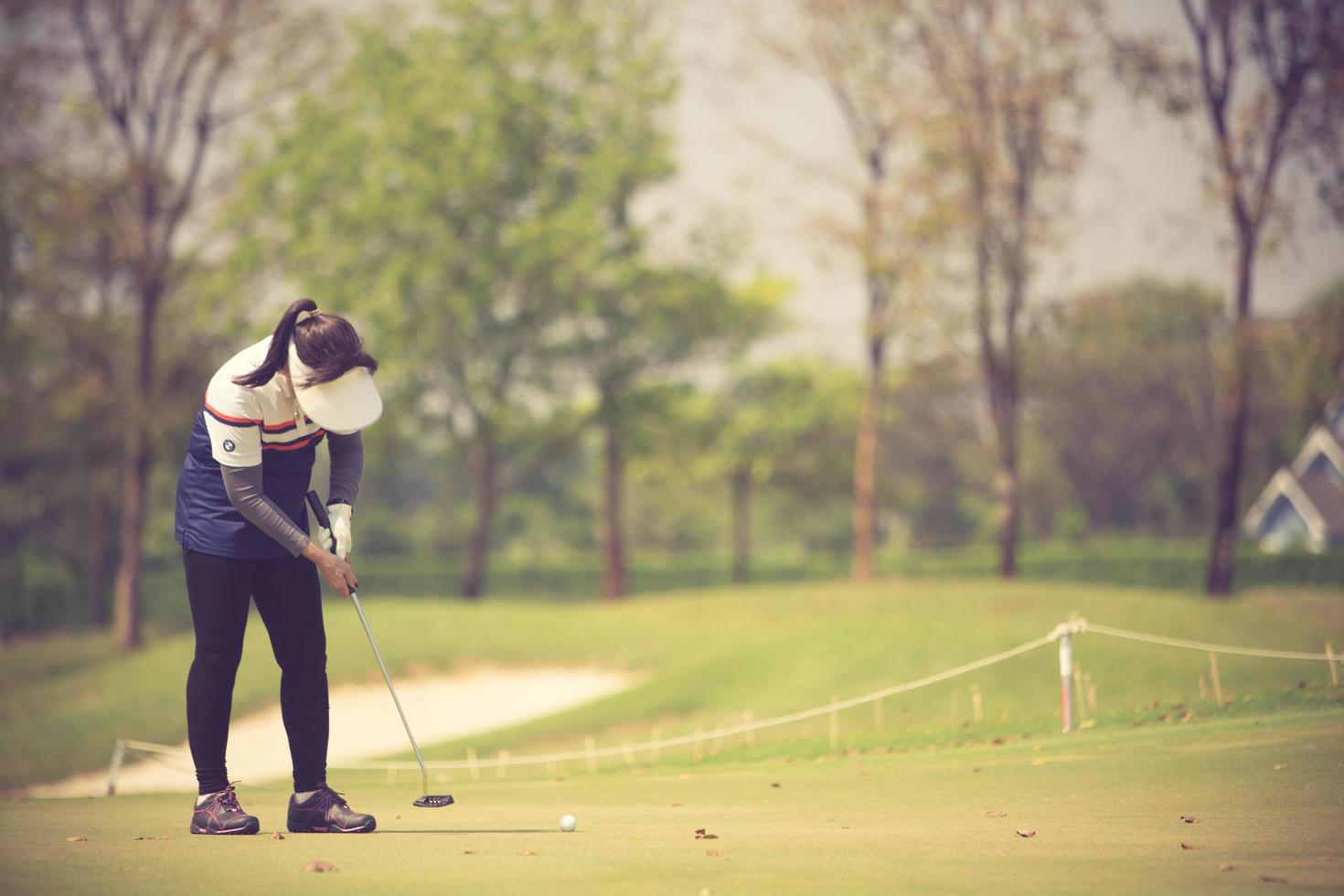 jugador de golf en el putting green golpeando la bola en un agujero.color vintage foto