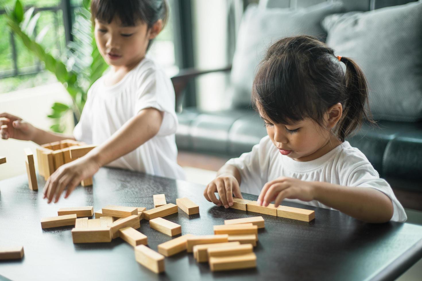 Two happy siblings playing a game with wooden blocks at home joyfully photo