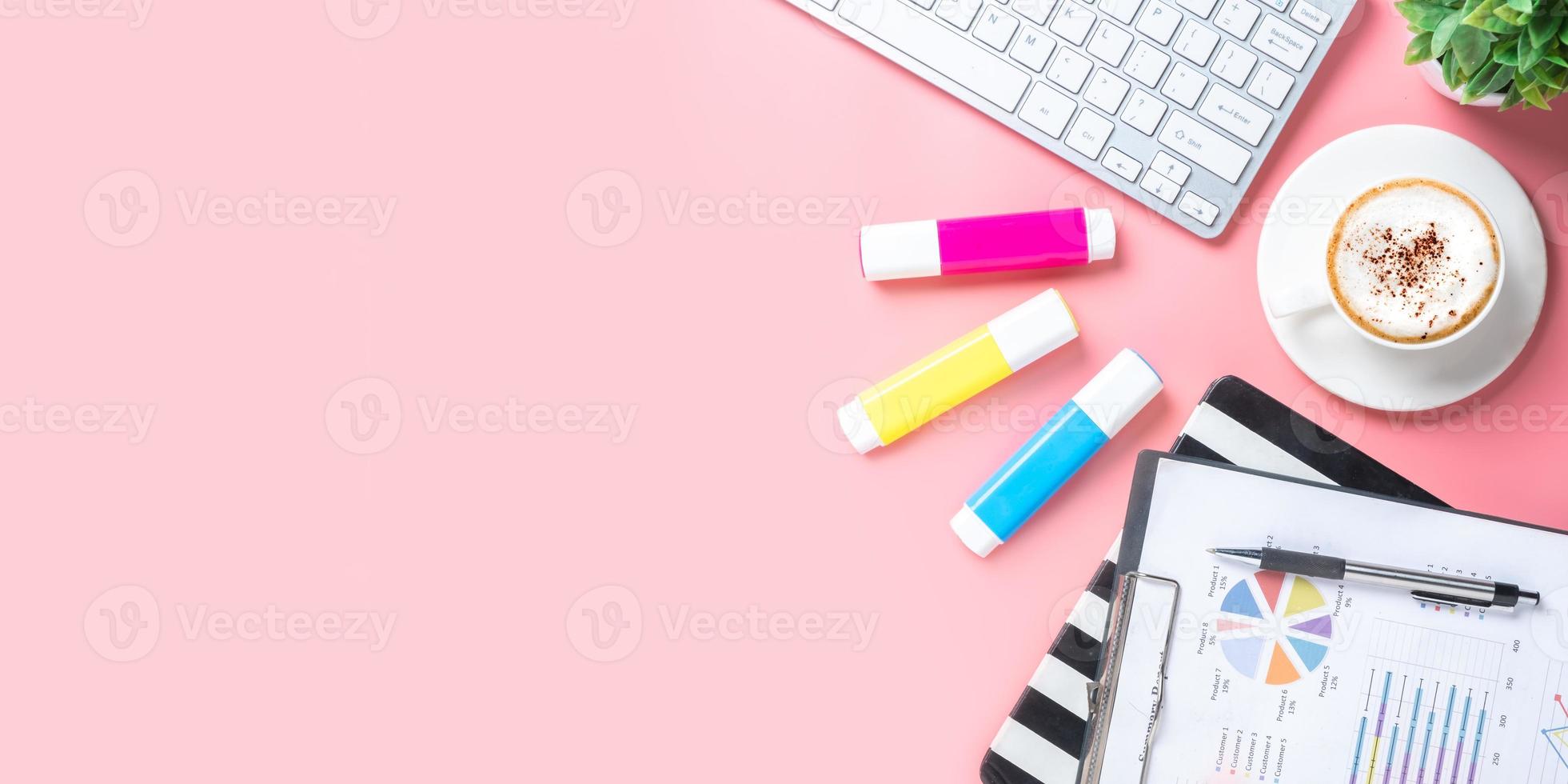 Office desk with keyboard computer, Pen, notebook, Cup of coffee on pink background, Top view with copy space, Mock up. photo