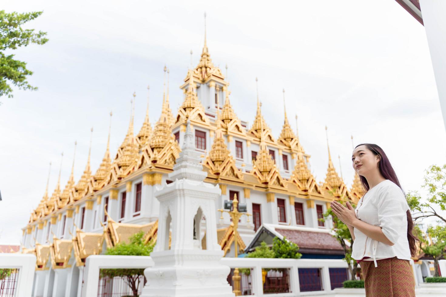 A young woman praying at Wat Ratchanatdaram a famous tourist attraction and places of interest in Bangkok Thailand photo