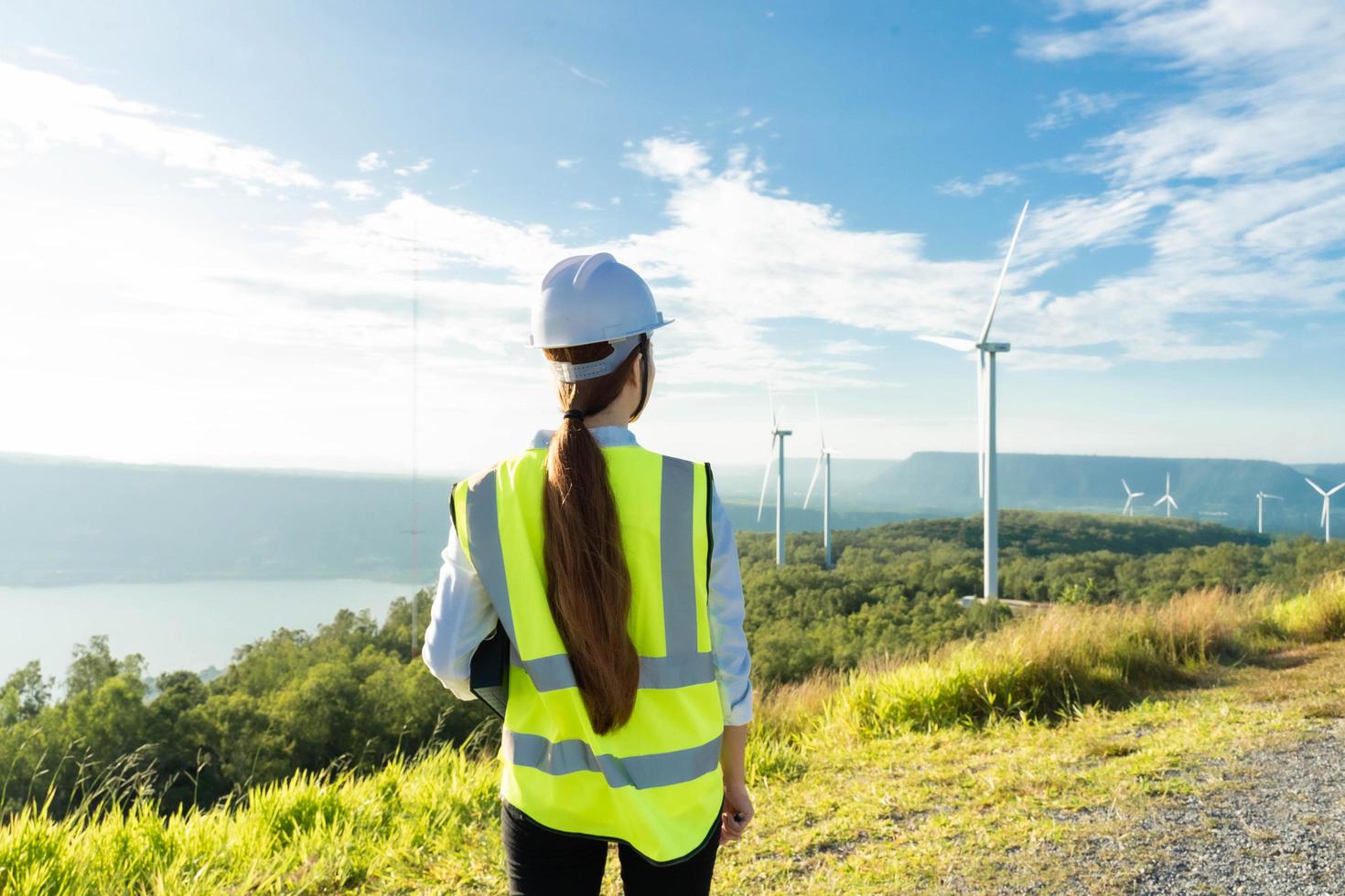 Engineer looks at wind turbine in the field. Maintenance of wind generator. Green renewable energy photo