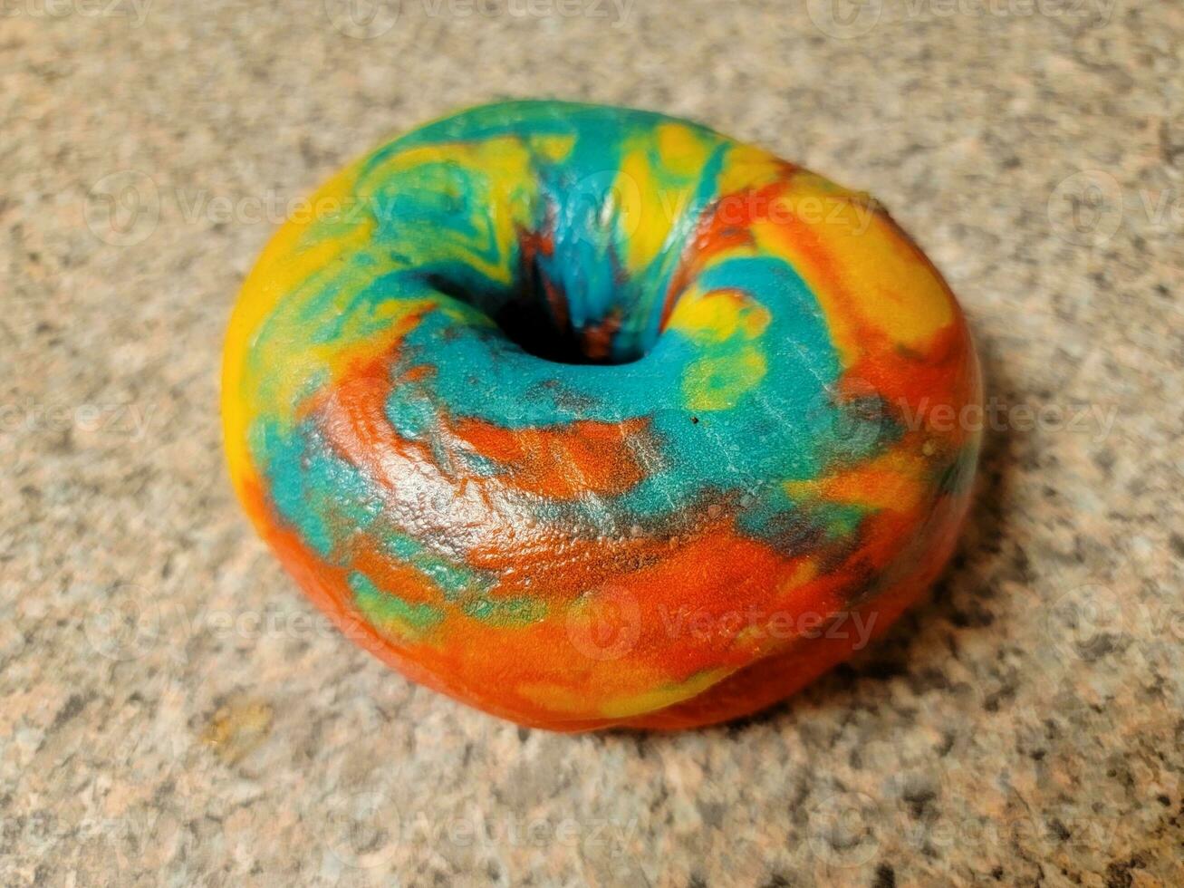 colorful bright rainbow bagel with many colors on counter photo