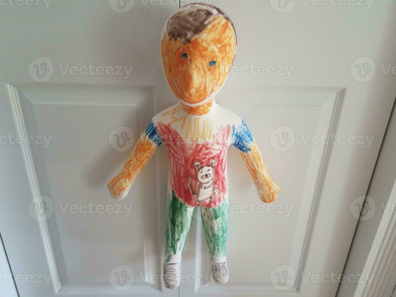 creepy colorful boy or child mannequin or doll hanging on door photo