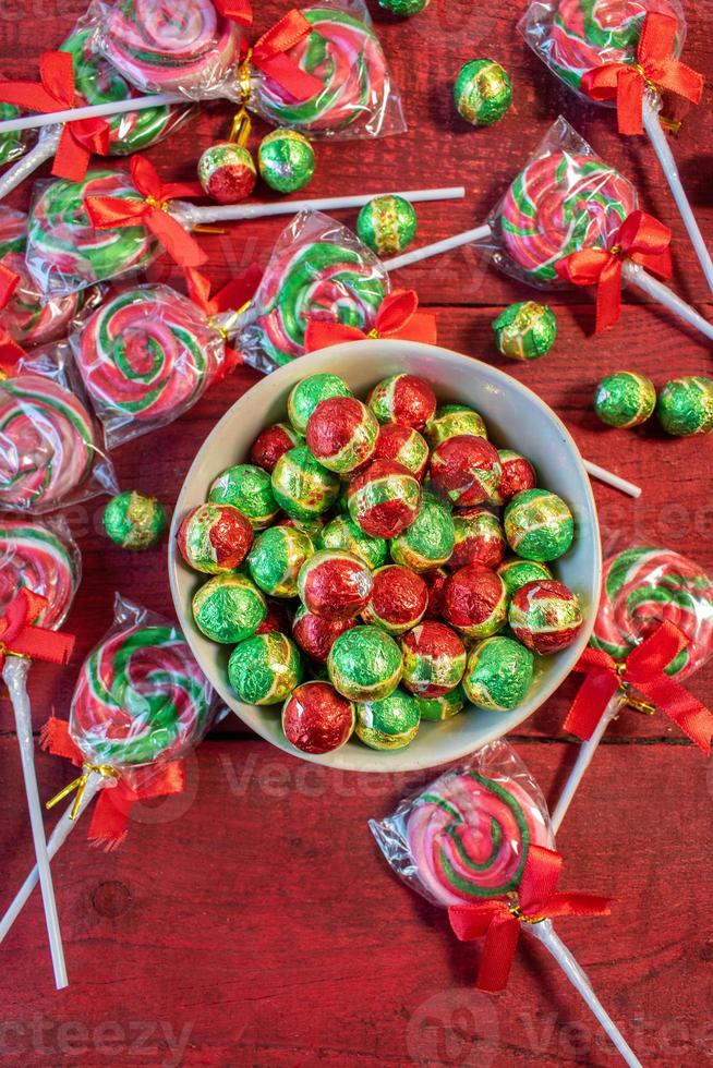 Christmas candy chocolates and lollypops on red background flat lay photo