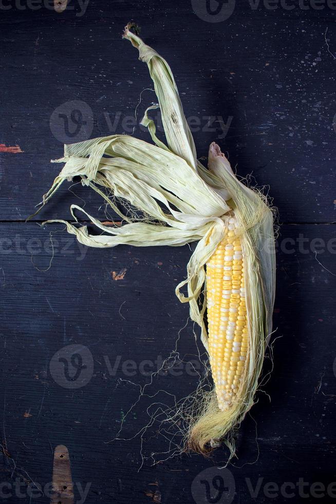 whole sweet corn with husks on table photo