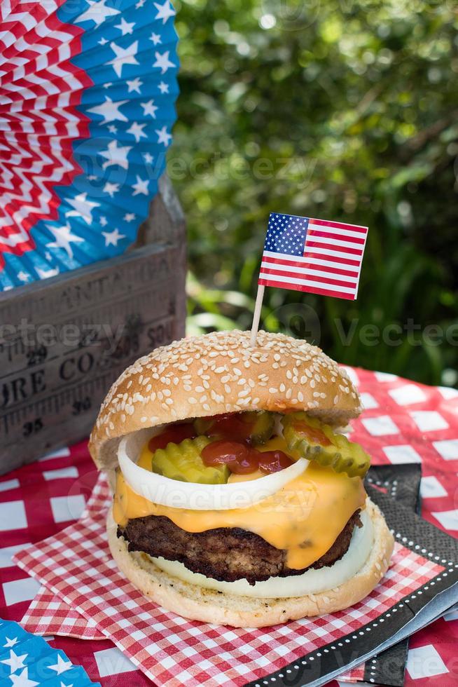 Fourth of July cheese burger with American flag on picnic table outdoors photo