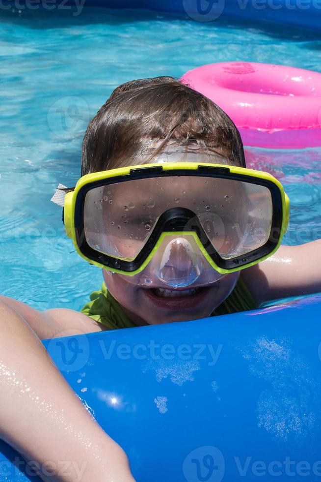 smiling young boy in swim goggles at pool photo