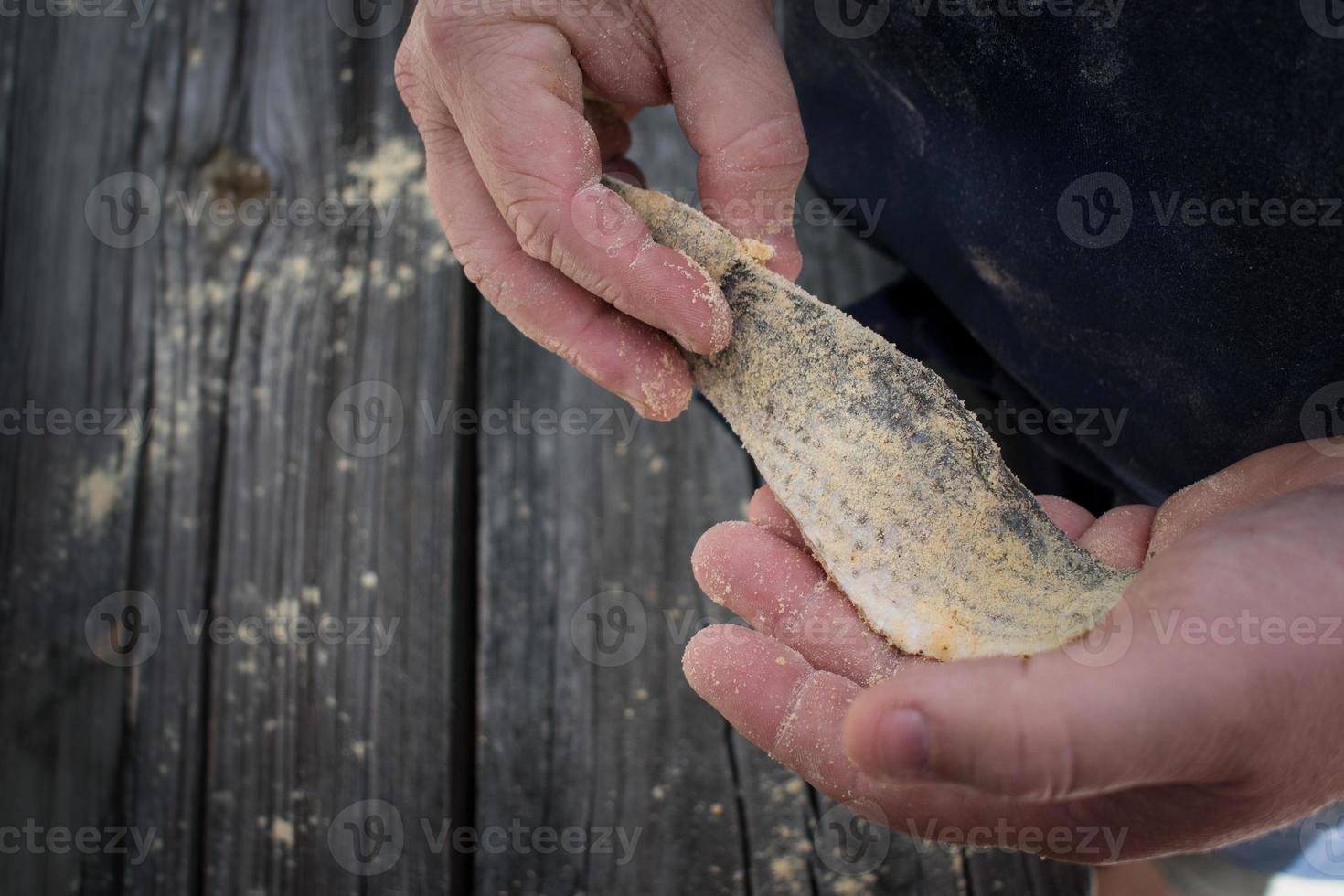 manos sosteniendo filete de salmonete empanado para freír pescado foto