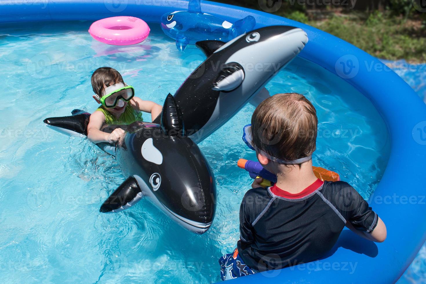 two boys riding swim floats in pool with goggles photo