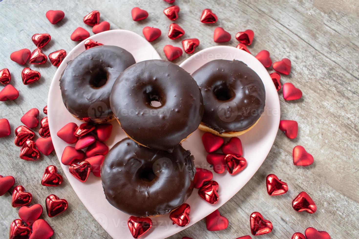 chocolate covered doughnuts on heart shaped plate surrounded by Valentine hearts photo