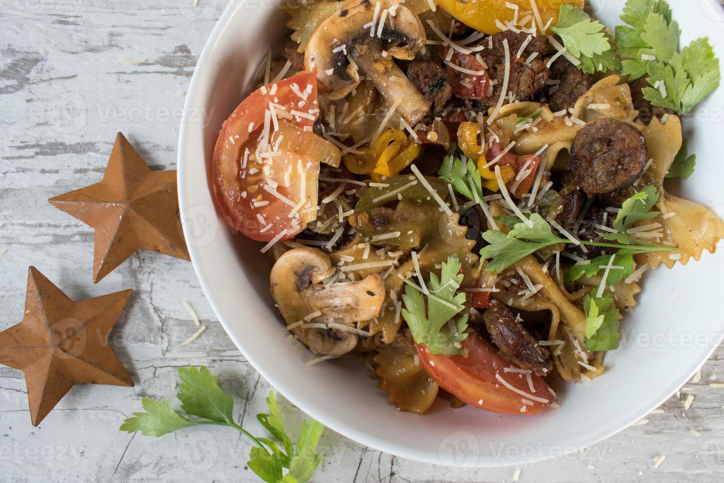 pasta de pajarita con tomates y champiñones espolvoreados con queso y hierbas foto