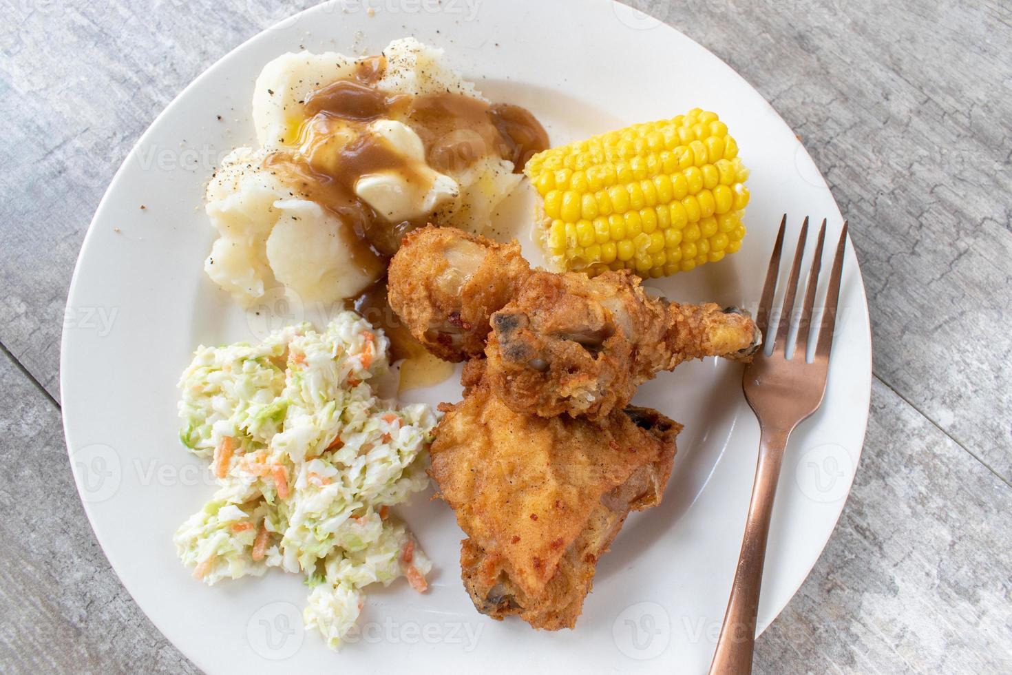 Plated flat lay of fried chicken with mash potatoes and corn on the cob photo