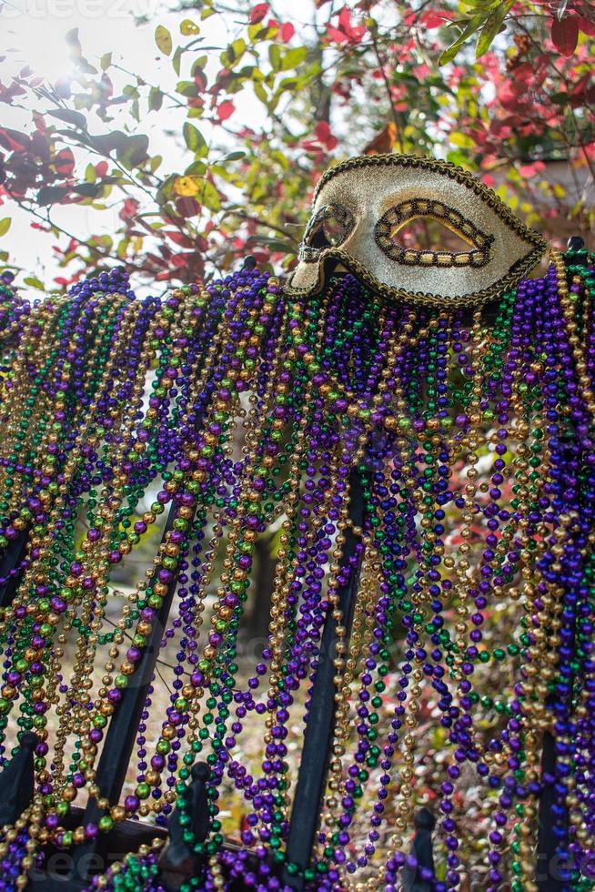 Mardi Gras beads covering wrought iron fence with carnival mask photo