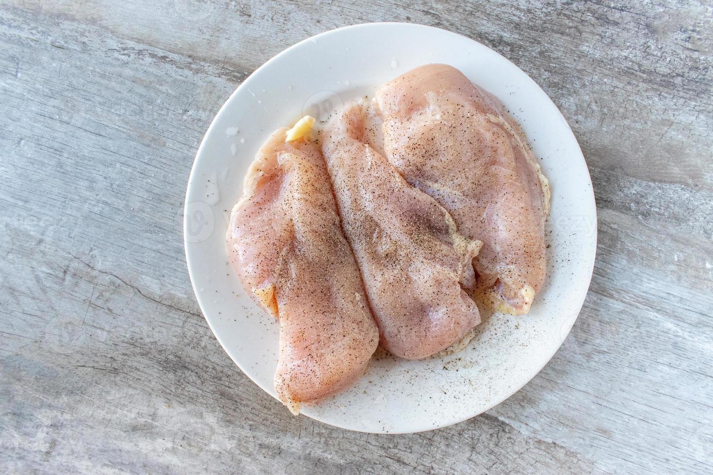 three raw chicken breasts with seasoning flat lay photo