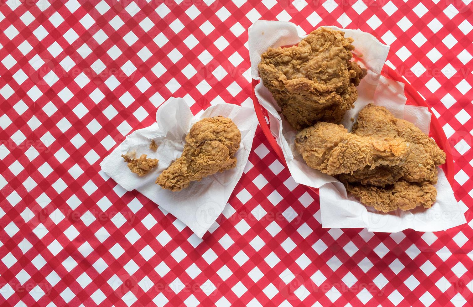 Fried chicken basket on red checkerboard tablecloth flat lay photo