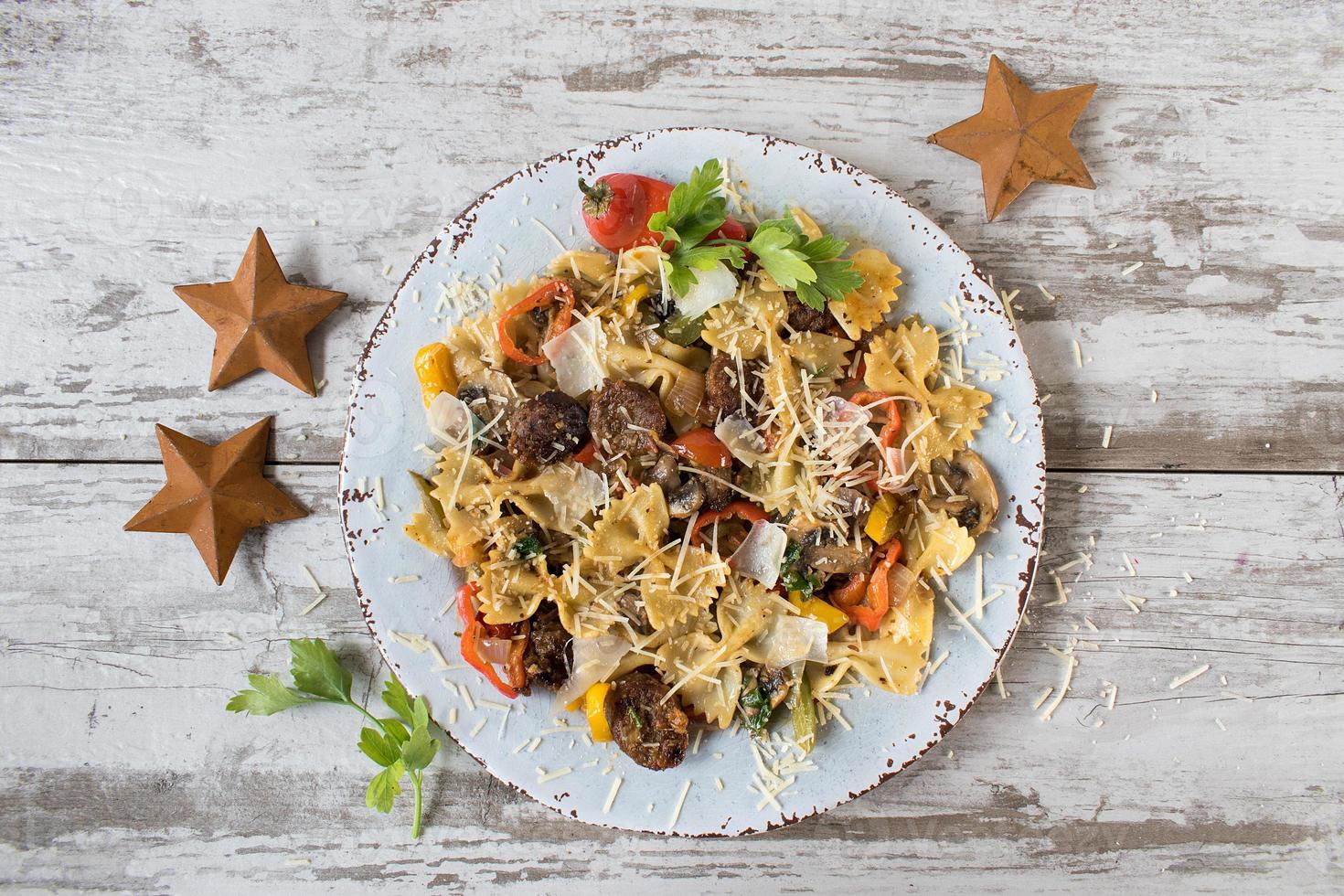 pasta de pajarita con tomates y champiñones espolvoreados con queso y hierbas planas foto