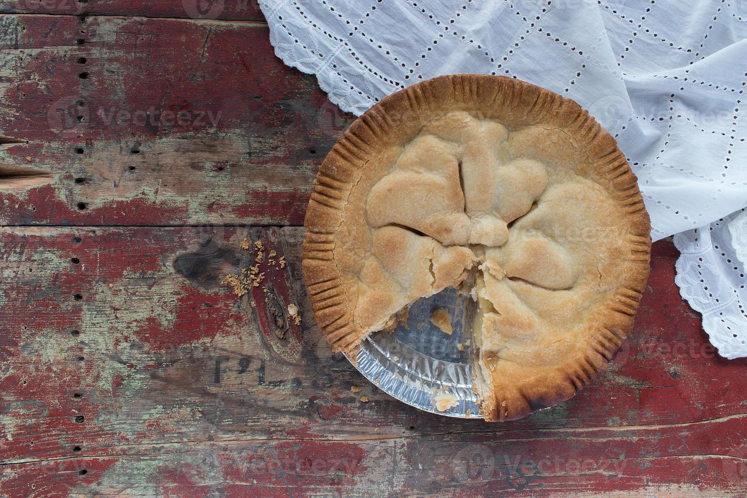 Homemade whole country apple pie on red painted wood table flat lay photo