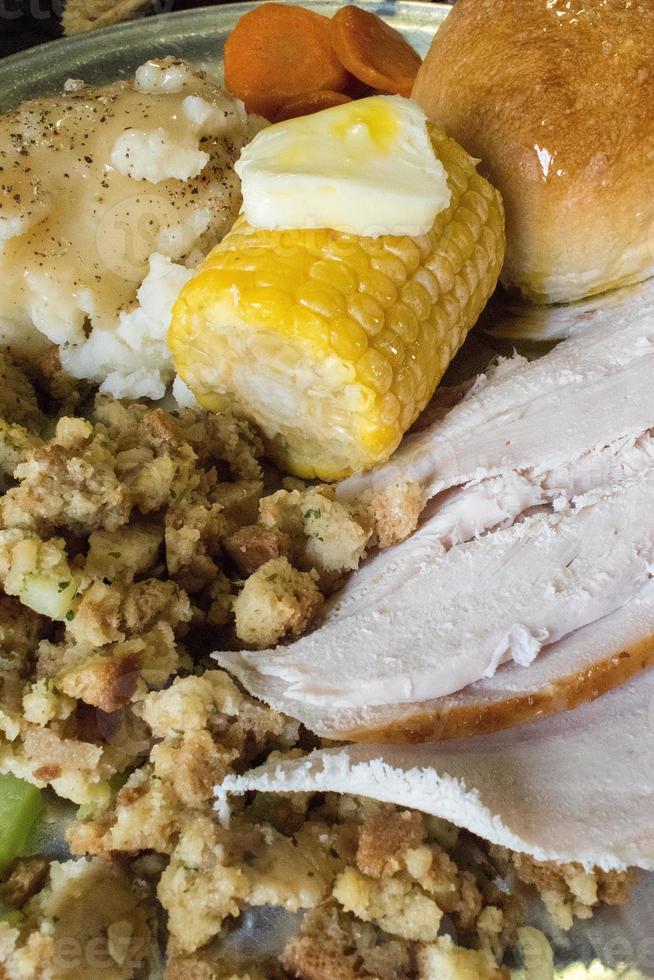 closeup of Thanksgiving meal of turkey, stuffing, corn, and bread photo