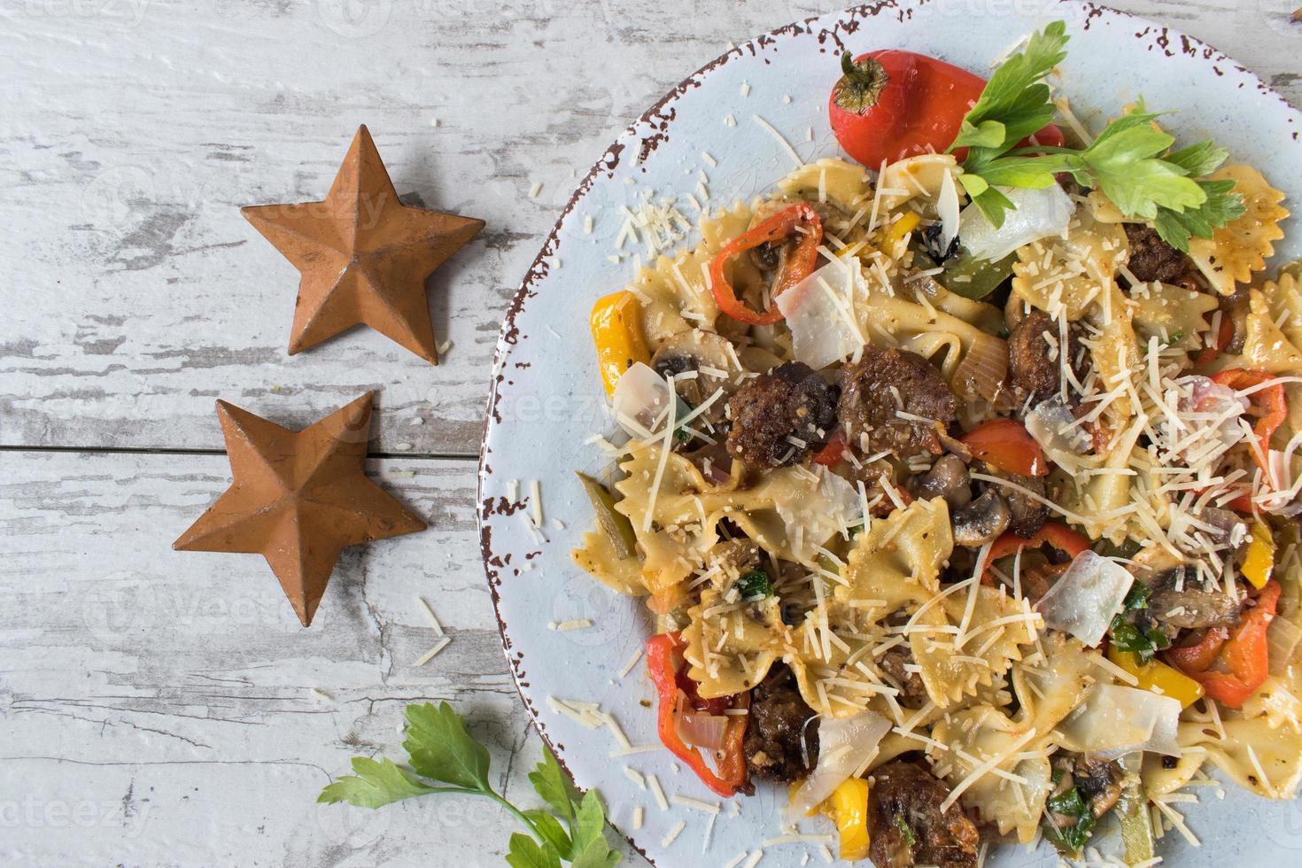 pasta de pajarita con tomates y champiñones espolvoreados con queso y hierbas foto