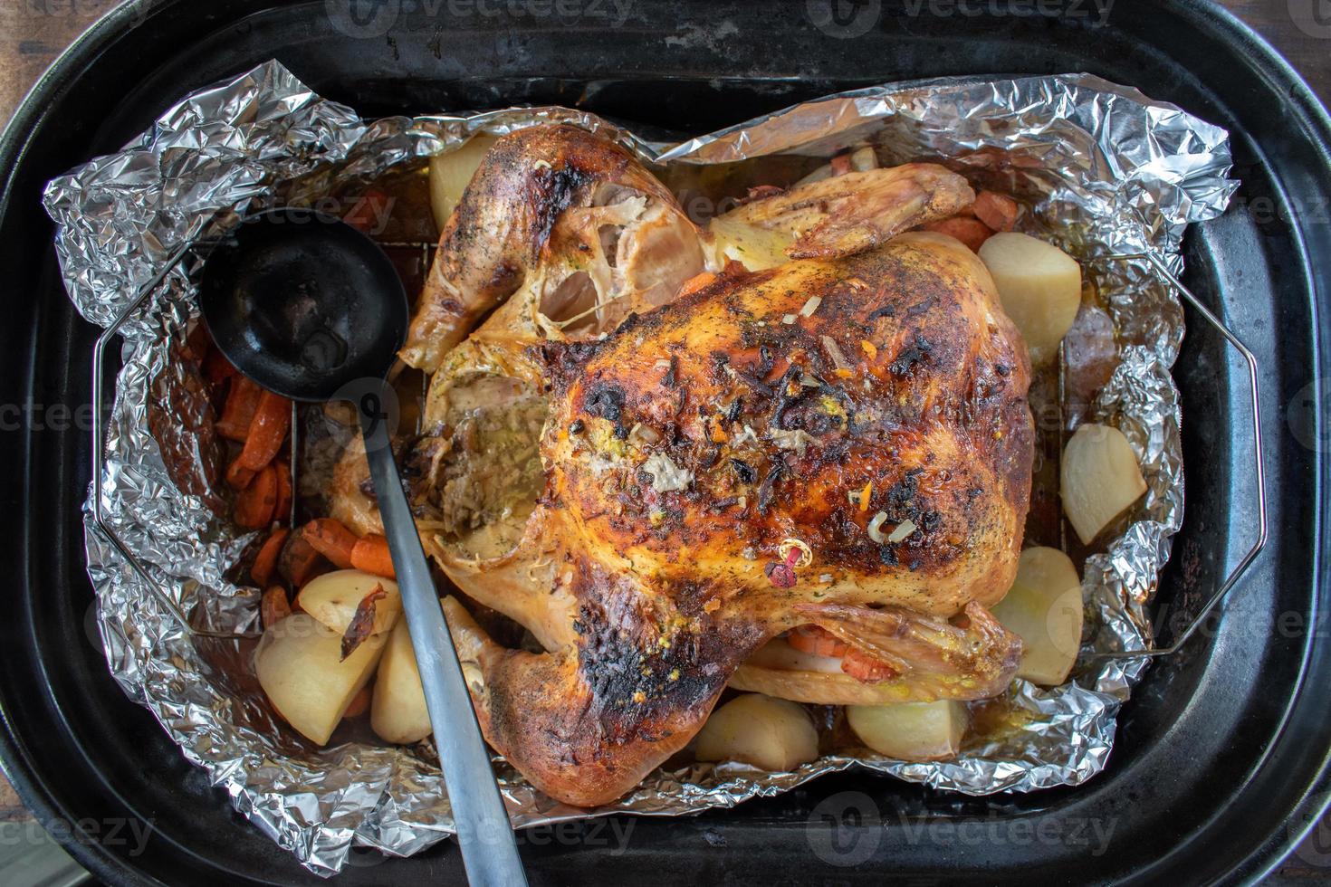 Thanksgiving baked turkey in roasting pan with potatoes and carrots photo