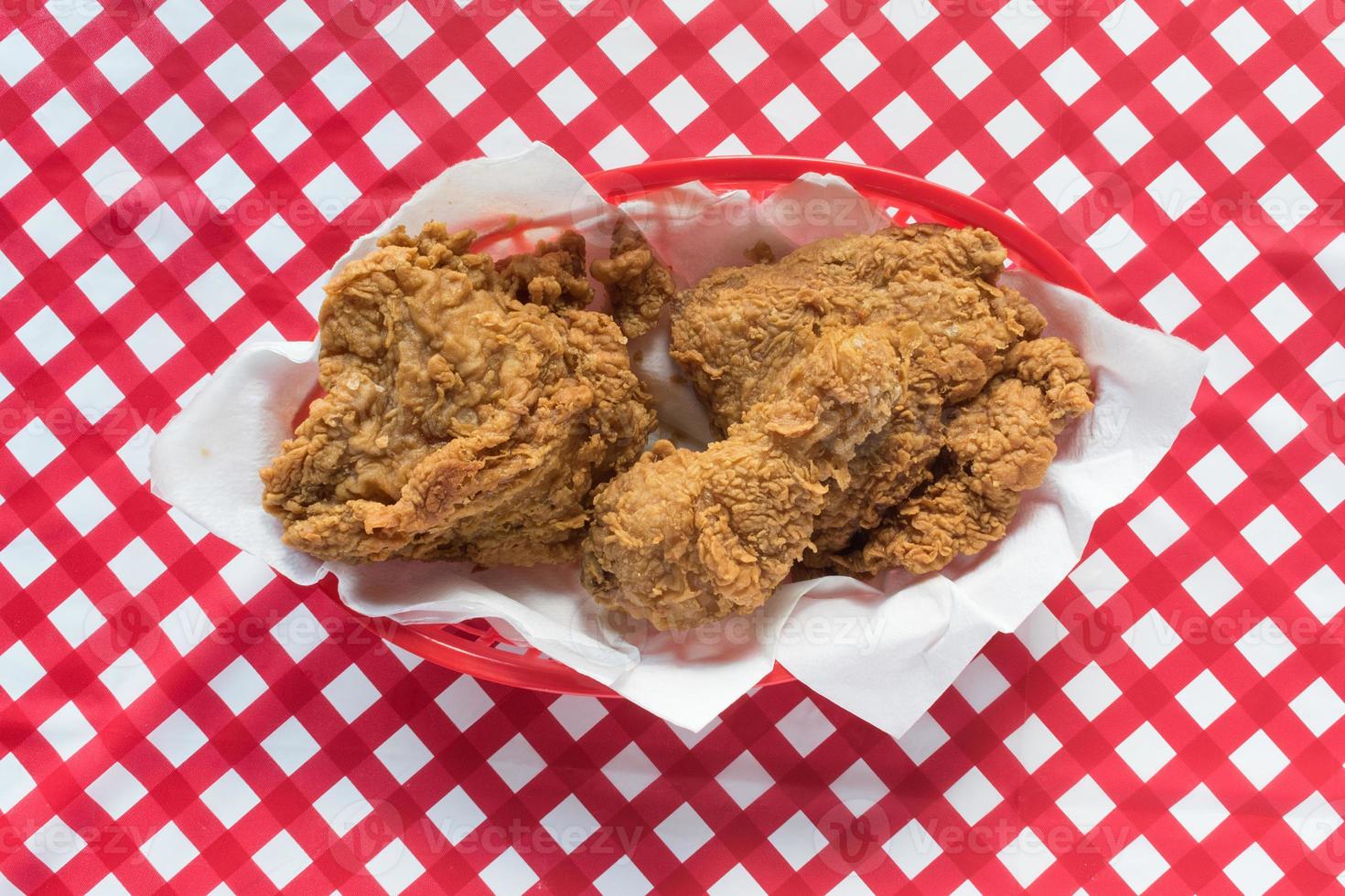 Fried chicken basket on red checkerboard tablecloth flat lay photo