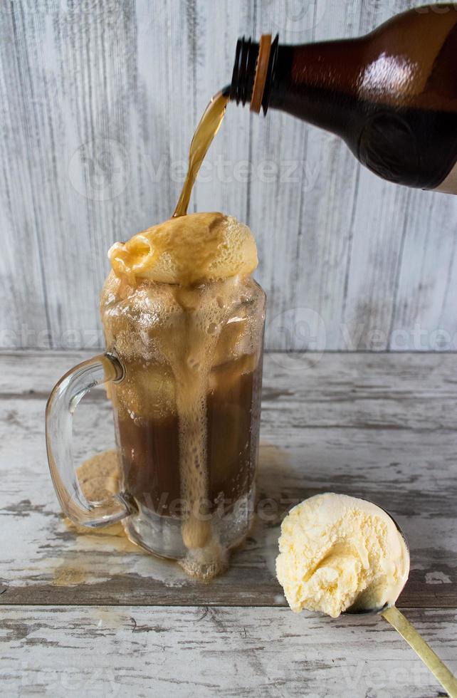 Verter flotador de cerveza de raíz con helado de vainilla en taza foto