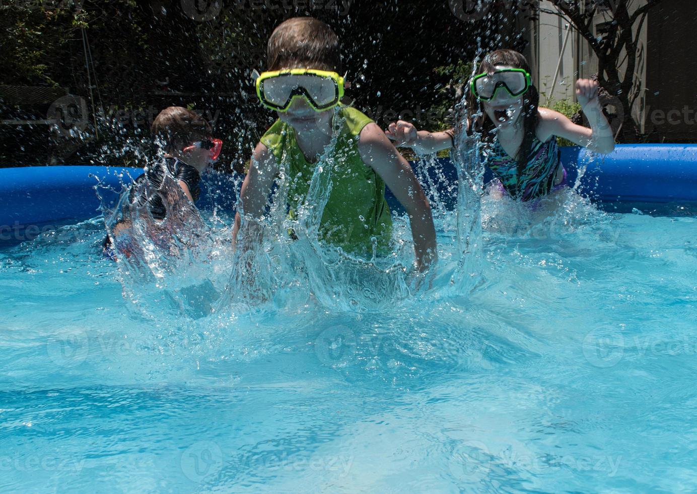 young kids running in water with goggles on in pool photo