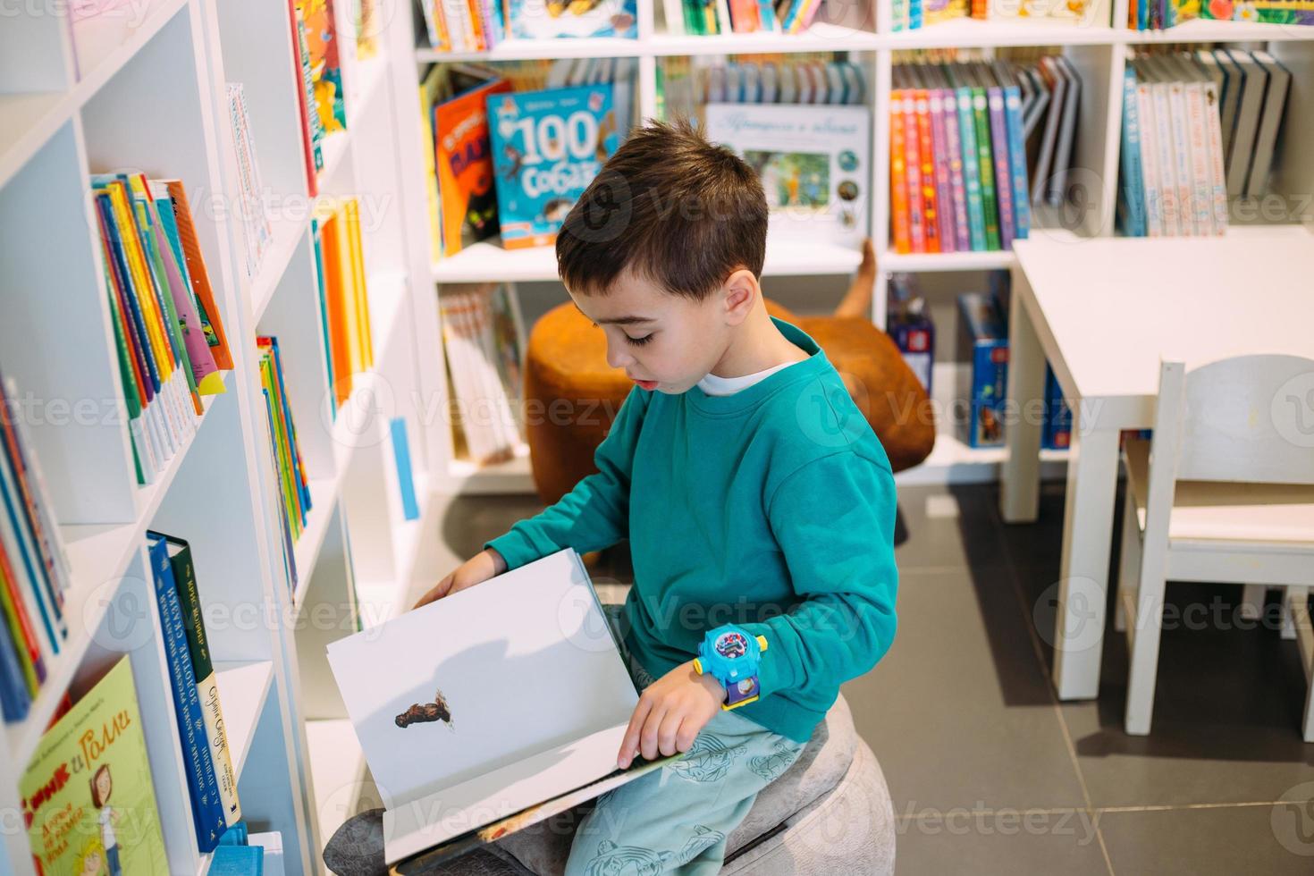 un niño alcanza un estante de libros para niños en la librería. foto