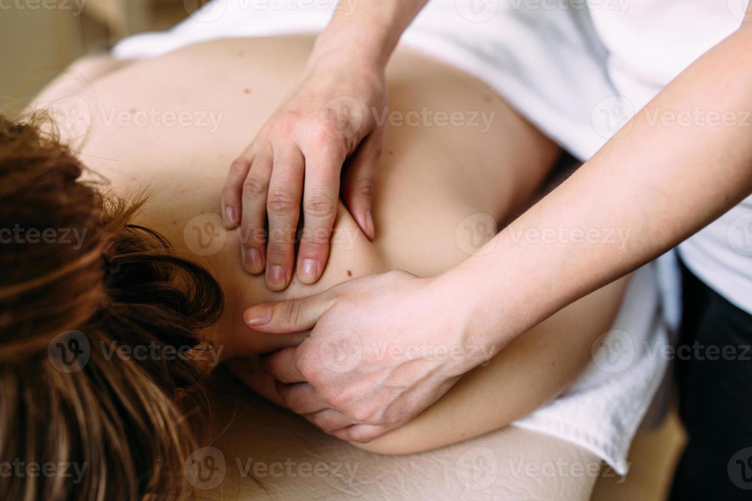 Massage therapist doing massage on the female body in the spa. The concept of cosmetic procedures. photo