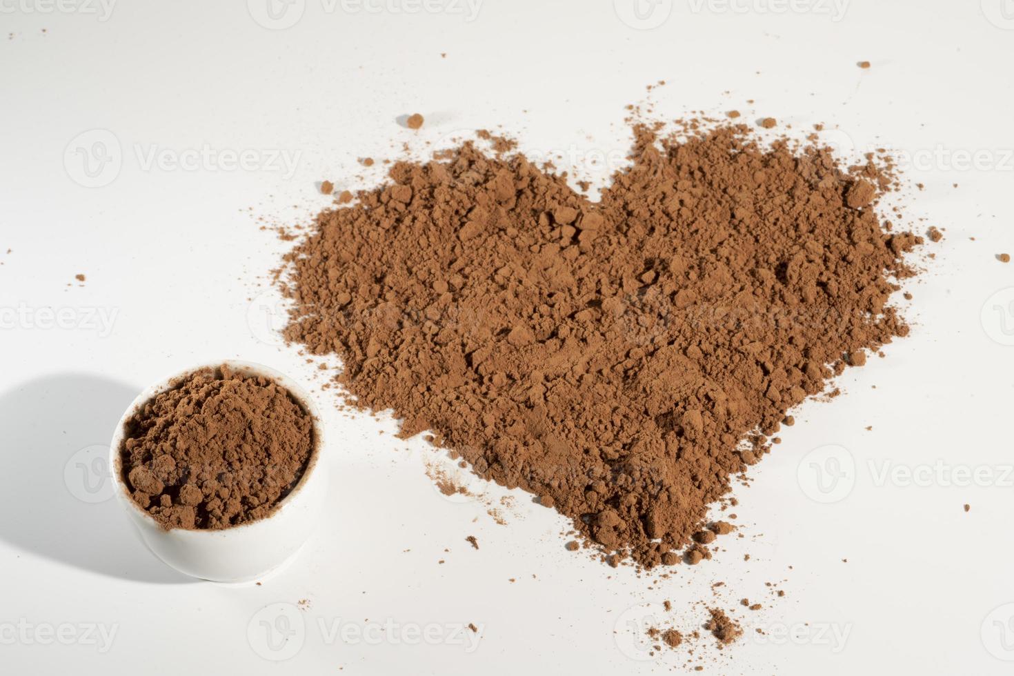 vierte cacao en polvo en forma de corazón, aislado sobre fondo blanco. foto