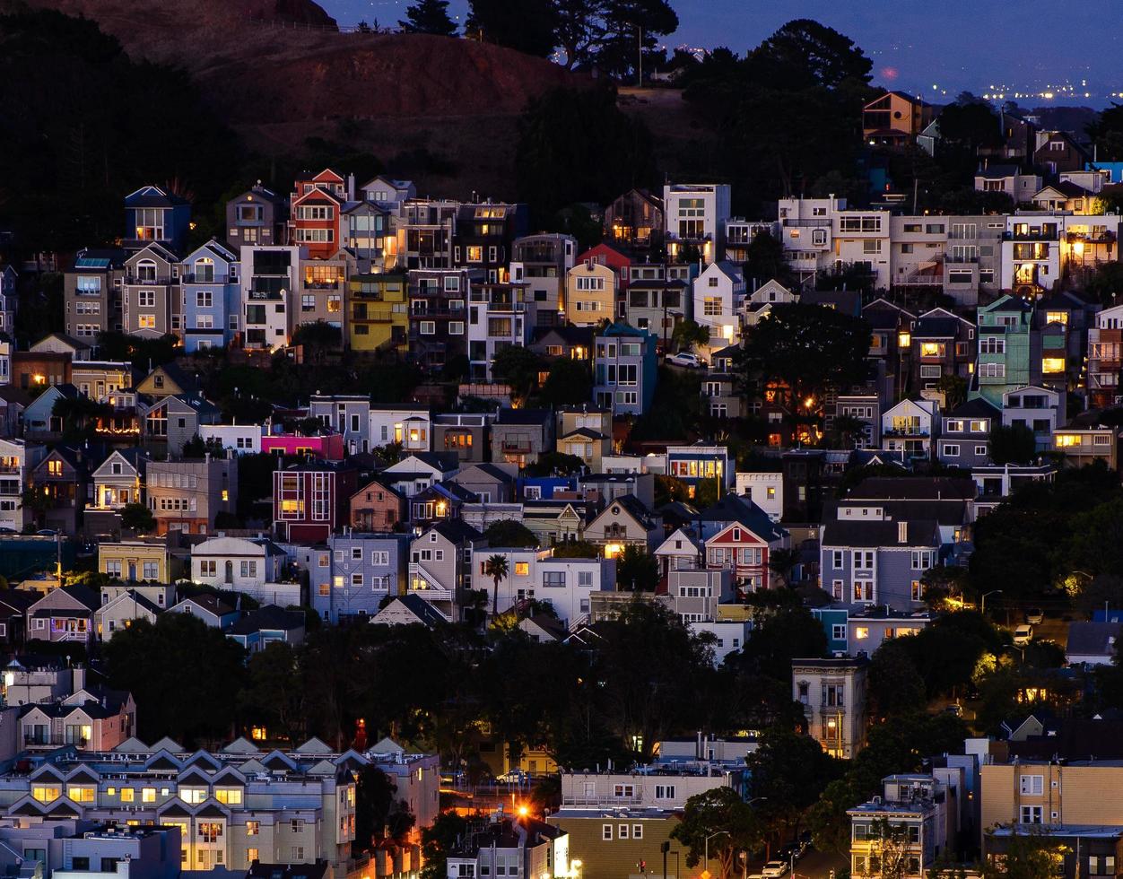 vista de la colina del vecindario de la hora dorada de las casas de san francisco, techos puntiagudos, coloridos y pintorescos con algunas casas victorianas, una vista típica de san francisco. foto