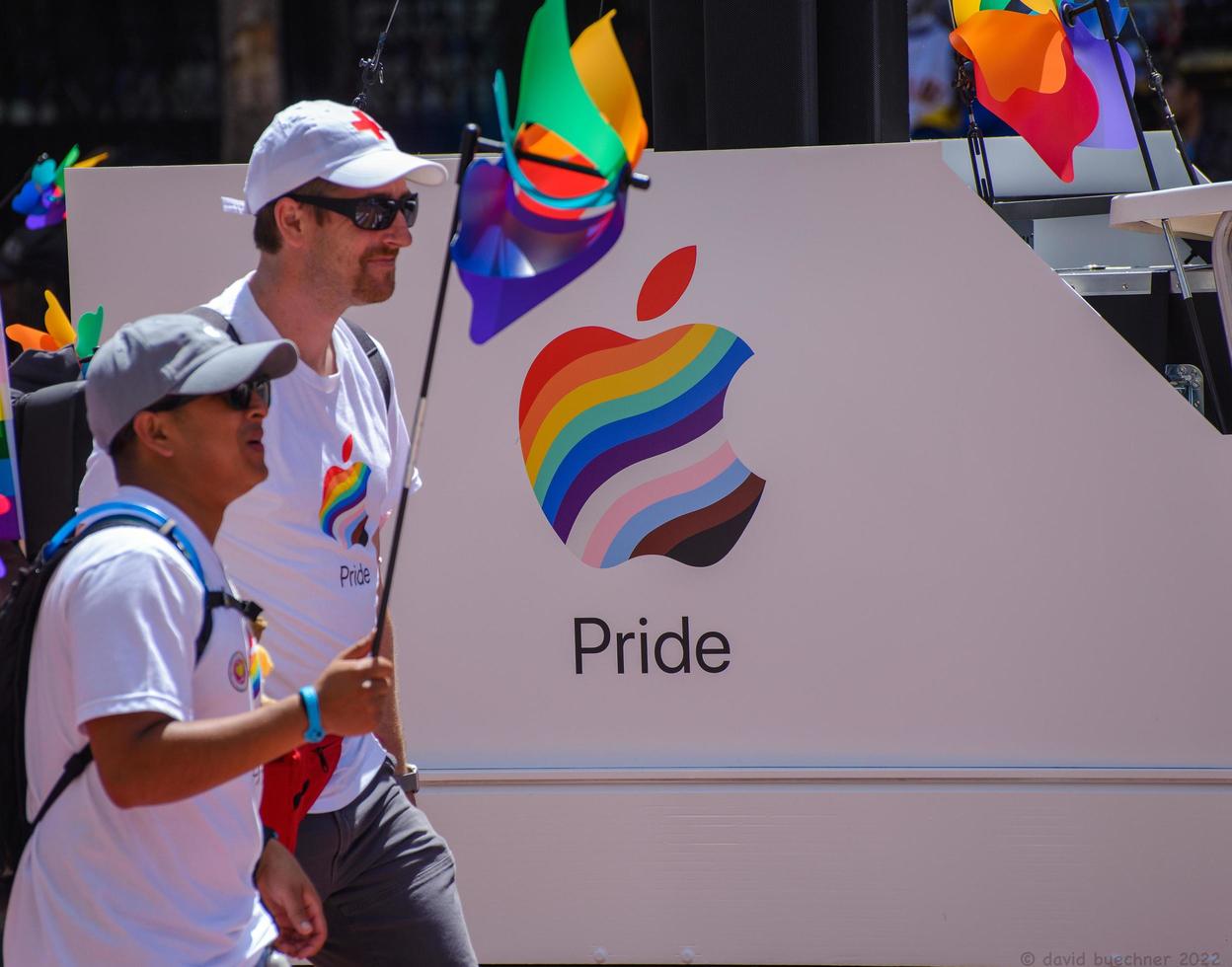 San Francisco, CA, USA - June 22, 2022, Pride Parade, Apple Corporation Contingent members carrying pride flag walking past Apple Pride logo photo