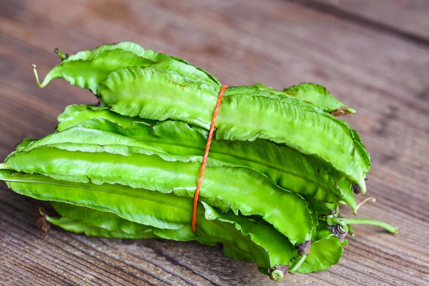 frijol alado sobre fondo de madera, psophocarpus tetragonolobus - frijoles verdes alados o de cuatro ángulos foto