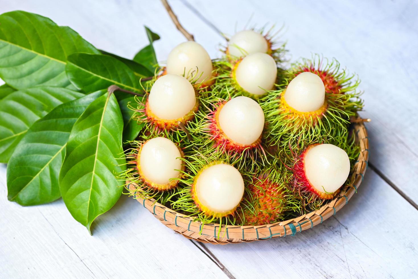 rambután fresco y maduro fruta tropical dulce rambután pelado con hoja, fruta de rambután en el fondo de la cesta cosecha del árbol de rambután del jardín foto