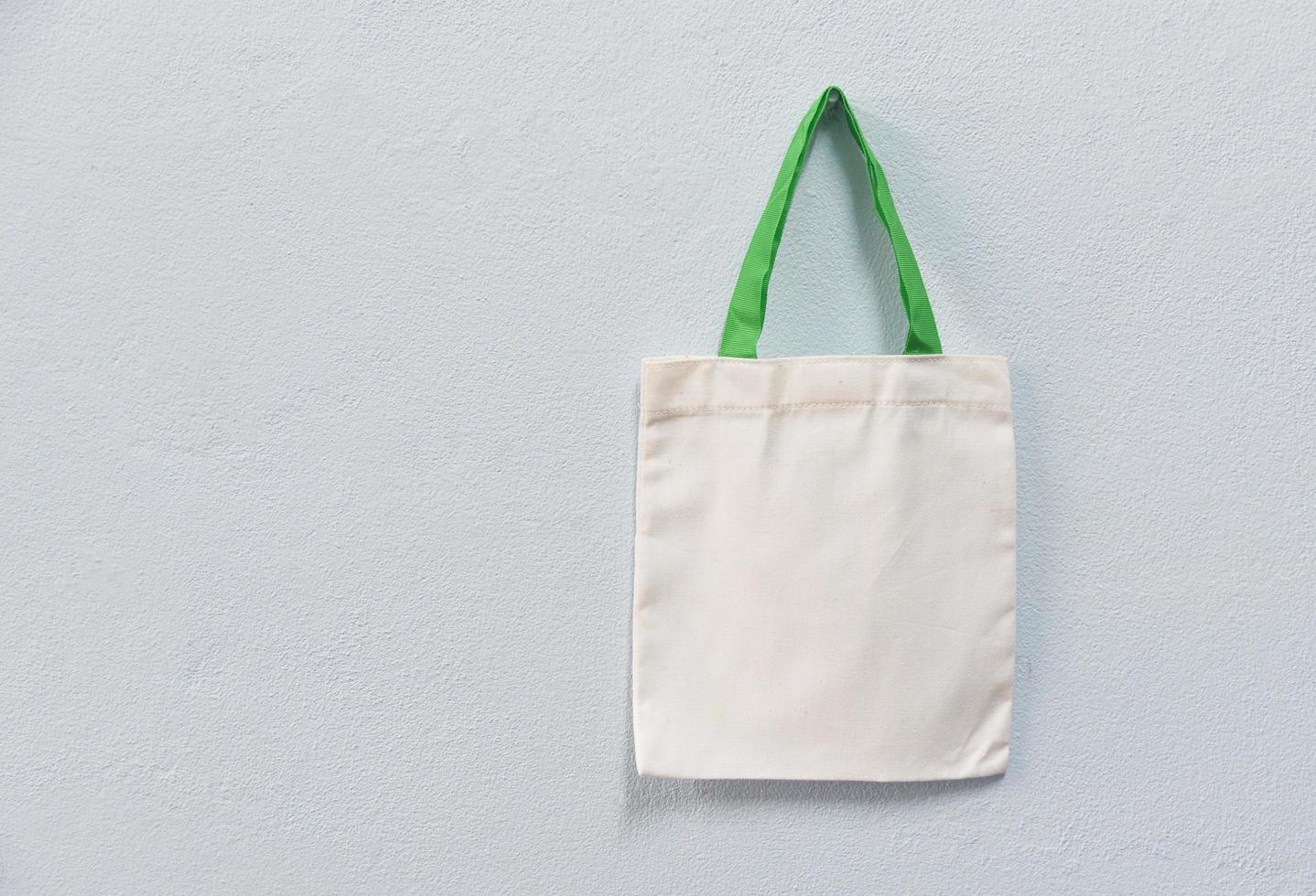 White tote canvas fabric eco bag cloth shopping sack on wall background photo