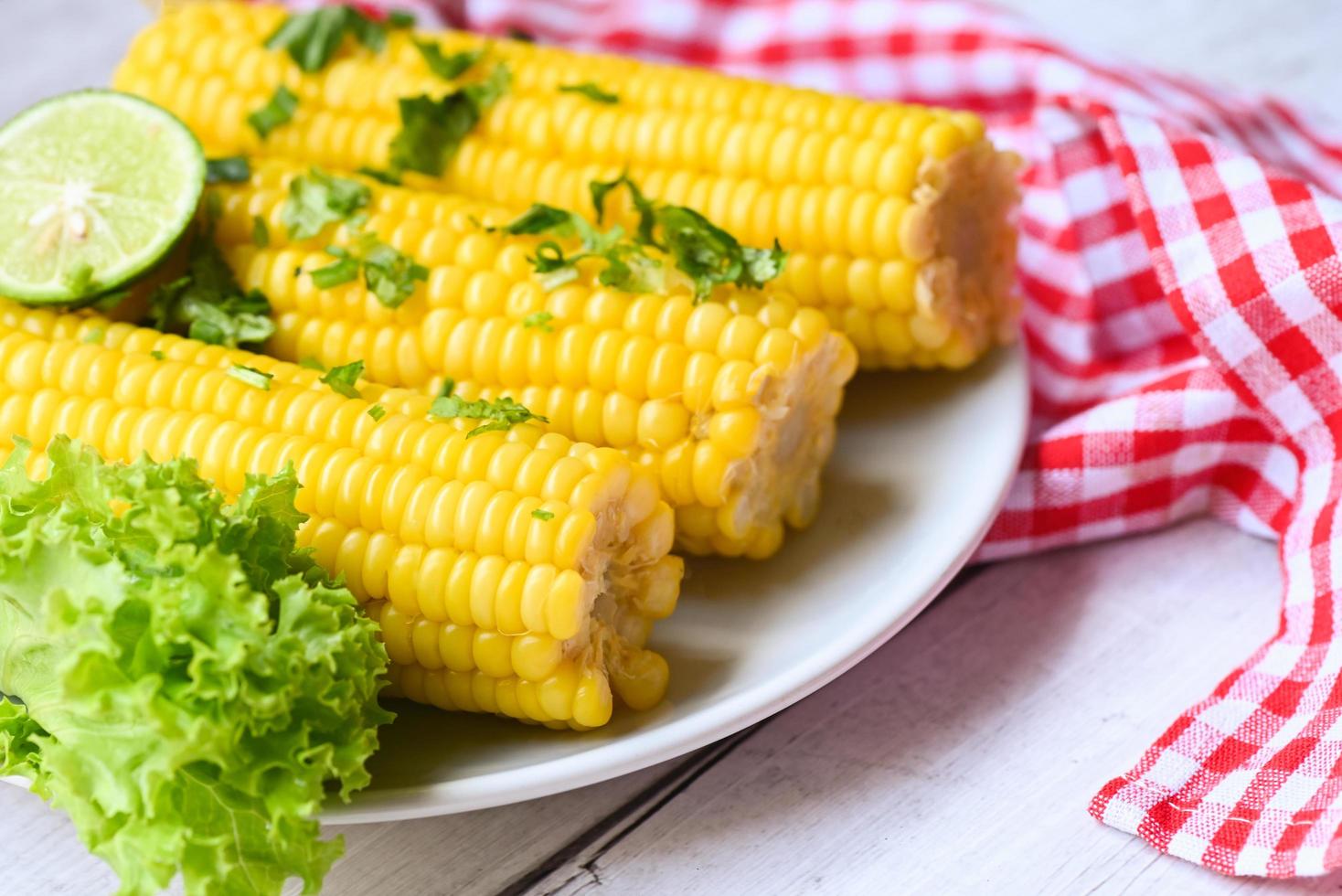 sweet corn food with salad vegetable lime coriander and lettuce, sweet corn cooked on white plate background, ripe corn cobs steamed or boiled sweetcorn for food vegan dinner or snack photo