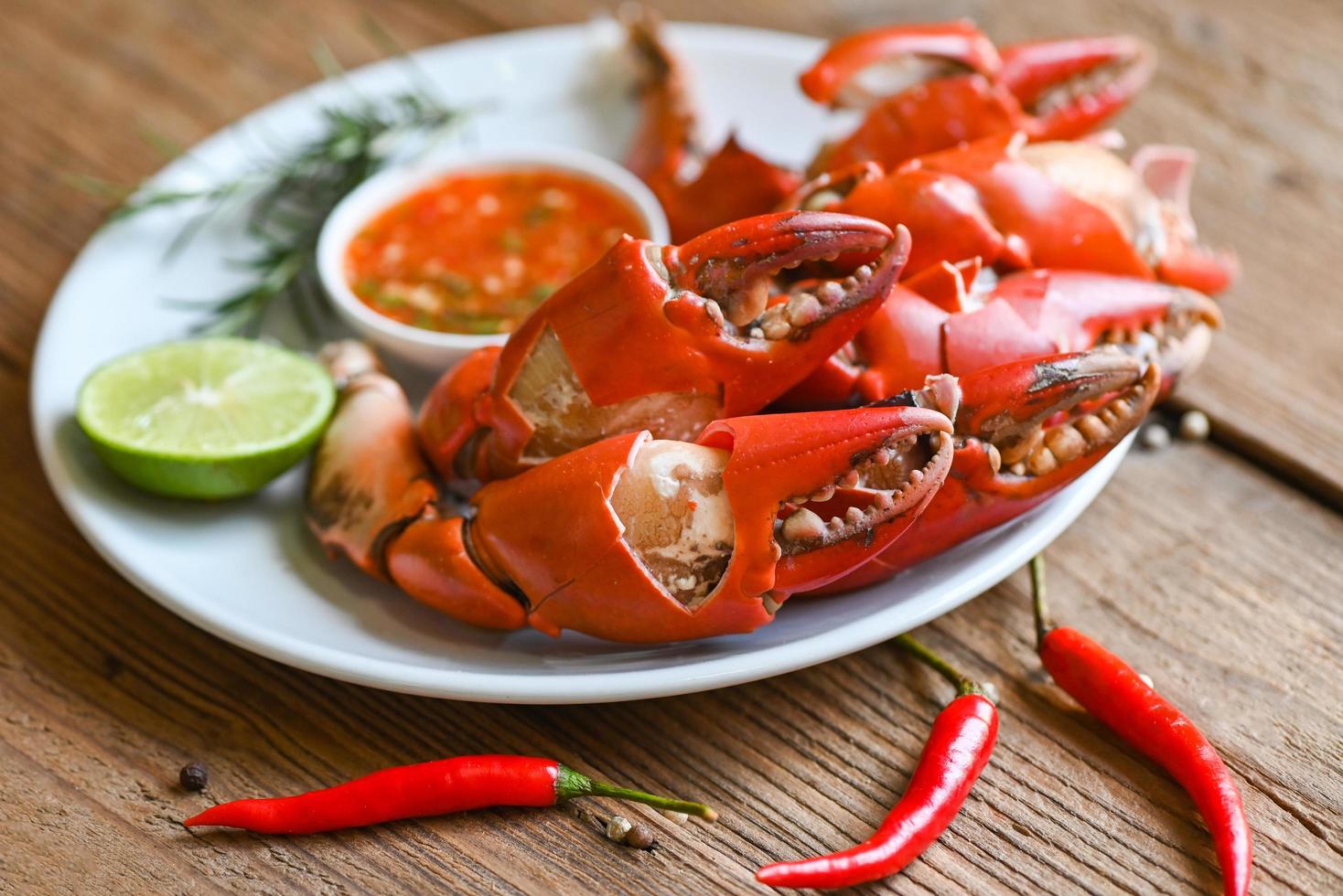 Cangrejo de garra cocinando comida plato de mariscos con hierbas picantes especias ensalada de lima limón, cangrejo fresco en plato blanco salsa de mariscos, cangrejo rojo hervido o al vapor en el restaurante foto