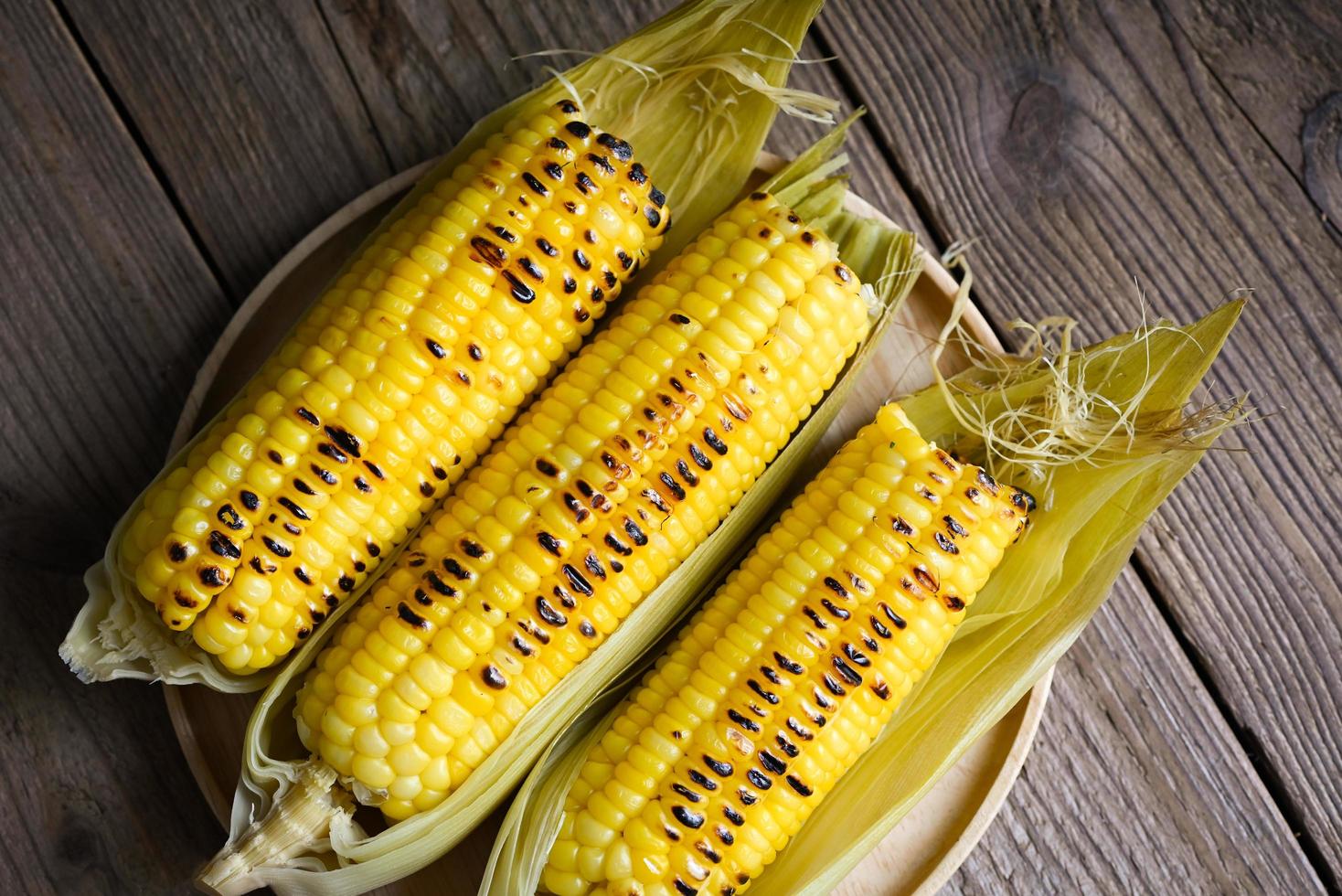 sweet corn food , sweet corn cooked on wooden plate background, ripe corn cobs grilled sweetcorn for food vegan dinner or snack - top view photo