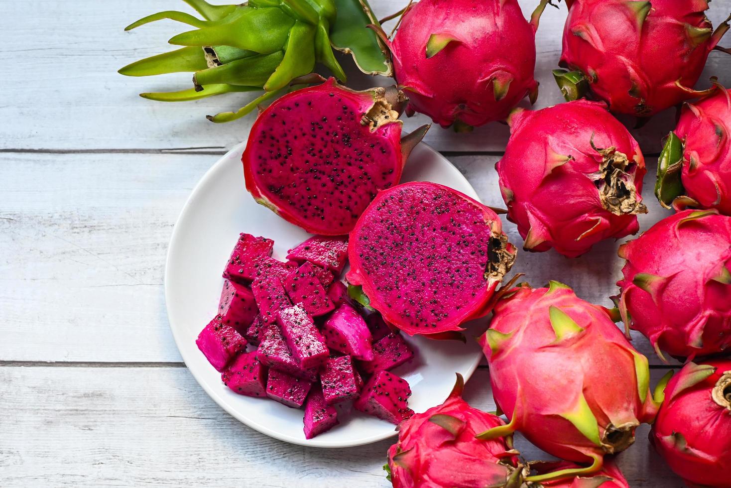 Rebanada de fruta de dragón y cortada a la mitad en un plato blanco con fondo de pitahaya, fruta de dragón púrpura roja fresca tropical en el concepto de fruta saludable de Tailandia asiática - vista superior foto