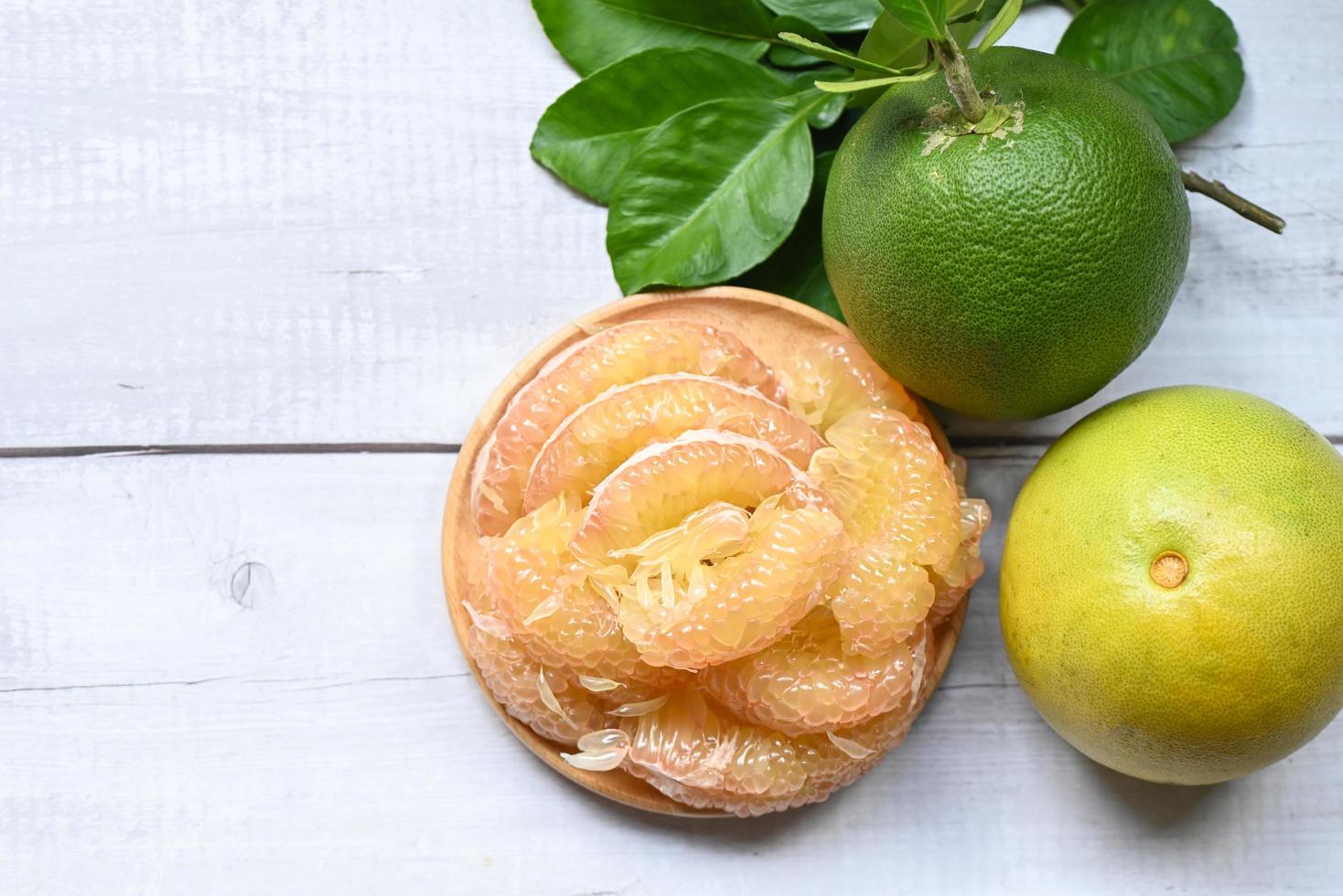 pomelo fruit on wooden plate  background, fresh green pomelo peeled and leaf frome pomelo tree , pummelo , grapefruit in summer tropical fruit  in thailand photo