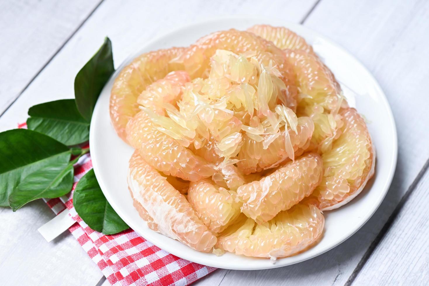 Pomelo fruit on white plate with leaf , fresh pomelo peeled frome pomelo tree , pummelo , Cloce up grapefruit in summer tropical fruit  in thailand photo