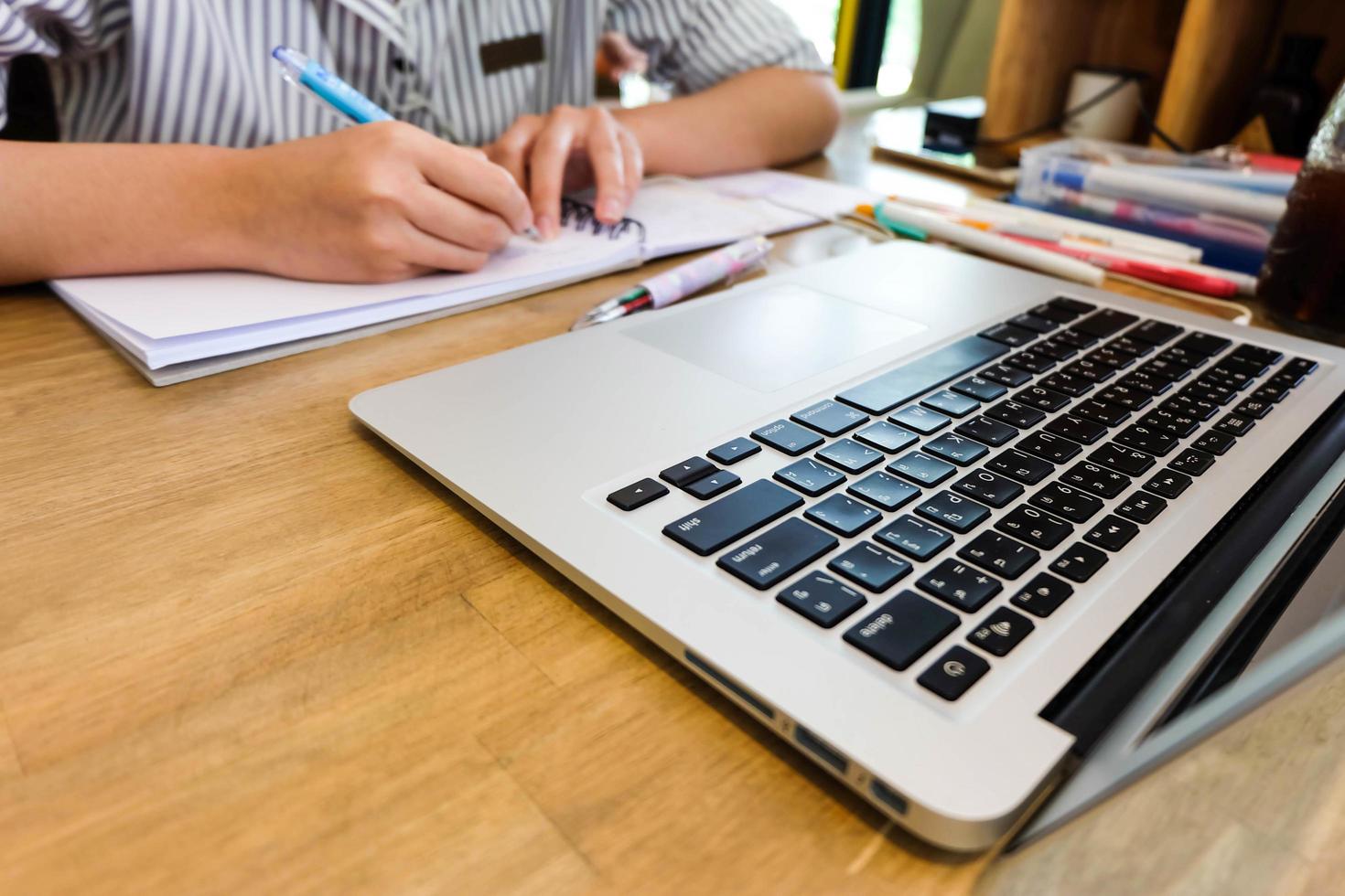 Young girl student is writing notebook and using laptop, learning and education concept photo