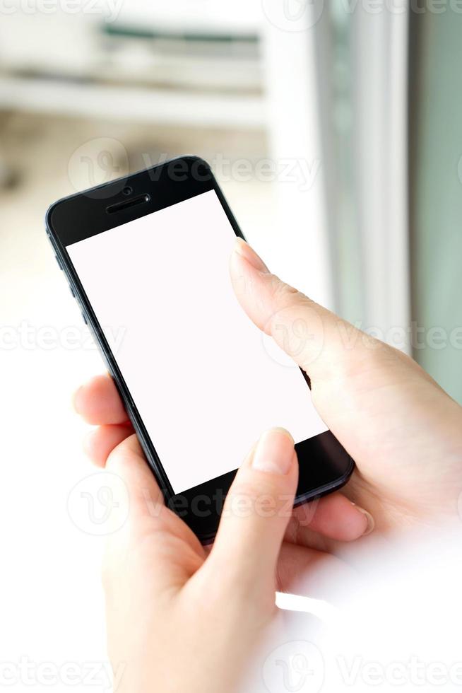 Woman with modern mobile phone in hands touching on a blank screen. photo