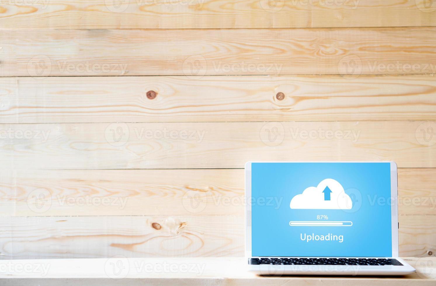 Cloud uploading on laptop  on wood table photo
