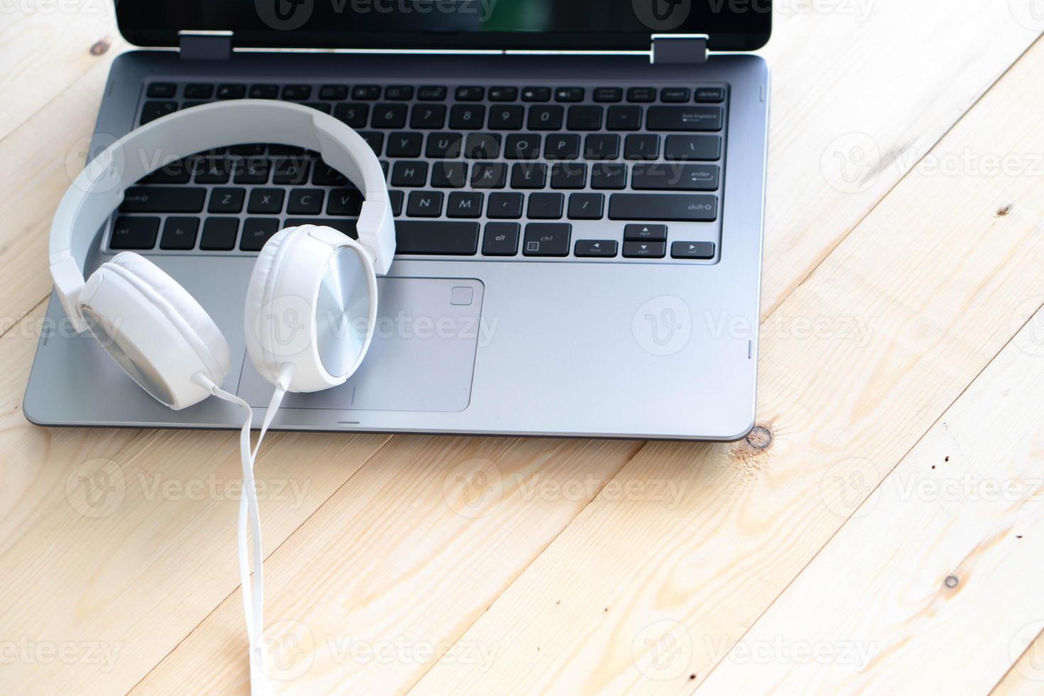 White headphone and laptop computer on wooden background photo