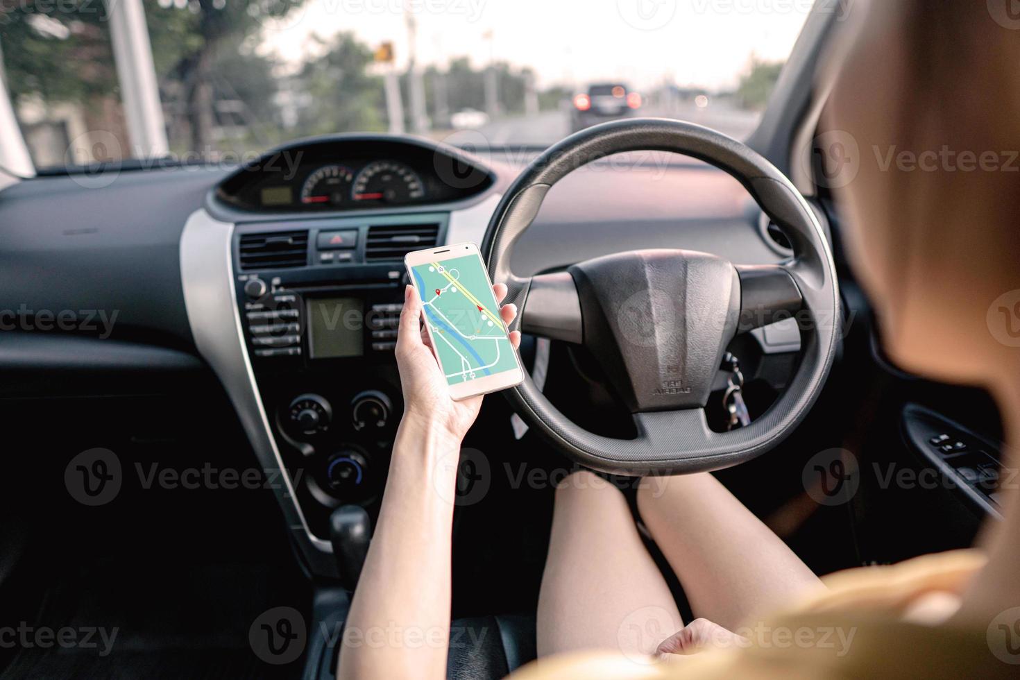 Woman in the car and holding mobile phone with map gps navigation photo